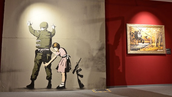 "Girl Frisking Soldier" von 2007 - Bild einer Replik von Kunst des Graffiti-Künstlers Banksy in der Hamburger Ausstellung "The Mystery of Banksy - A Genius Mind" © NDR Foto: Patricia Batlle