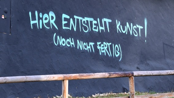 Ein Schriftzug mit dem Text: "Hier entsteht Kunst - noch nicht fertig" auf einer schwarzen Wand © picture alliance Foto: Pressebildagentur ULMER | ULMER Pressebildagentur