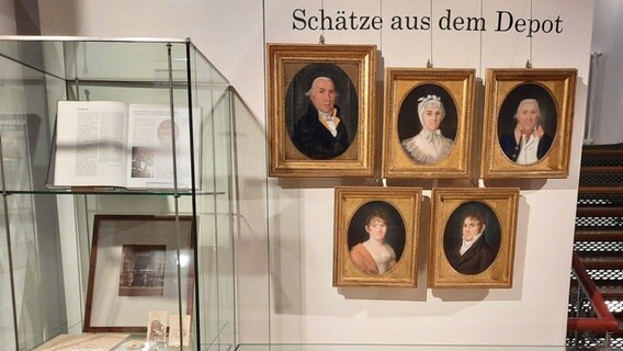 Fünf Porträts hängen neben einer Glasvitrine an einer Wand © Carlo Ihde / NDR.de Foto: Carlo Ihde