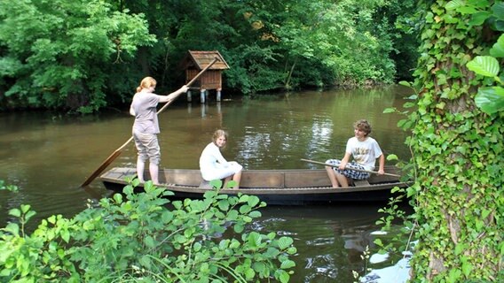 Kinder auf einem historischen Boot auf der Wümme, im Hintergrund ein für Fischerhude typisches Entenhaus, wie es sie auch vor 100 Jahren schon gab. © NDR Foto: NDR/Harald Ganswindt