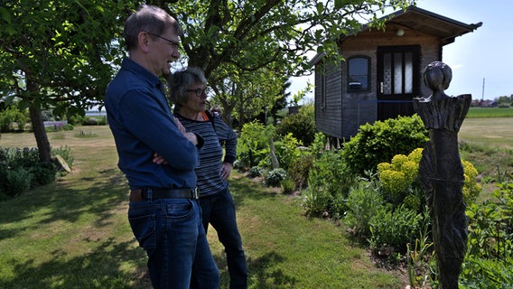 Ein Mann und eine Frau stehen im Garten von Carolin Platz aus Groß Karrendorf vor einer keramischen Figur. © Birgit Vitense Foto: Birgit Vitense