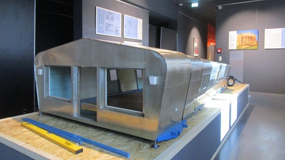 Ein silbernes Modell einer sogenannten Raumerweiterungshalle. Von vorne sieht es aus wie ein Wohnwagen, der nach hinten immer weiter geht. © Axel Seitz / NDR Foto: Axel Seitz / NDR