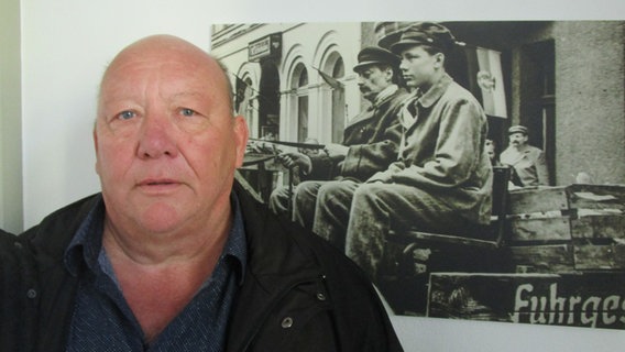 Michael Kröger steht vor einem Schwarz-Weiß-Foto, das an einer Wand hängt © Axel Seitz 