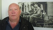 Michael Kröger steht vor einem Schwarz-Weiß-Foto, das an einer Wand hängt © Axel Seitz 