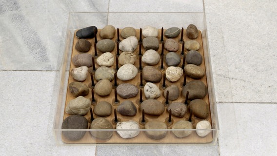 Nägel stecken in einem Brett, das auf dem Boden liegt. Dazwischen liegen Steine. © VG Bild-Kunst, Bonn 2013 