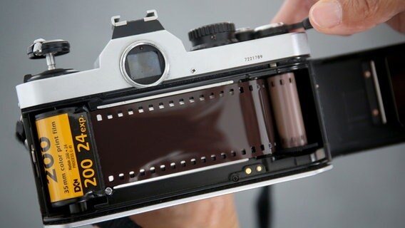 Ein analoger Fotoapparat, in den jemand gerade einen Film einlegt. © picture alliance/dpa Foto: Oliver Berg