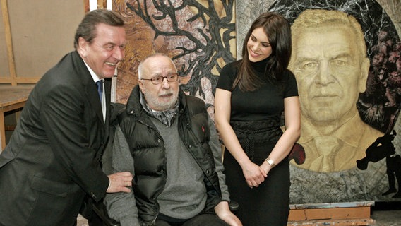 Der ehemalige Bundeskanzler Gerhard Schröder (l) bedankt sich bei dem Maler Jörg Immendorff und dessen Frau Oda Jaune 2007 in Düsseldorf für das Schröder-Porträt. © dpa Foto: Jörg Carstensen