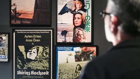 Der Filmemacher und Kurator der Ausstellung "Helma Sanders-Brahms · ihre Filme, ihr Leben", Ayhan Salar, schaut auf Filmplakate zu Werken von Helma Sanders-Brahms. © dpa Foto: Lennart Stock