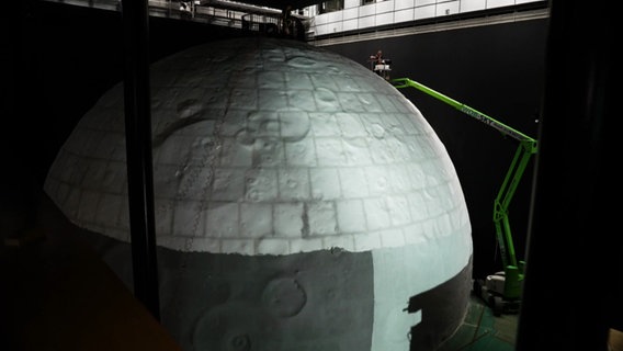 Eine Kuppel, die an einen Mond erinnert wird gerade im Museum aufgebaut. Eine Kuppel, die an einen Mond erinnert wird gerade im Museum aufgebaut. © NDR Screenshot