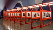 Eine Halle in moderner Architektur, in der rote Ausstellunswände mit Fotos hintereinander aufgereit sind. © Kunstmuseum Wolfsburg Foto: Kruszewski