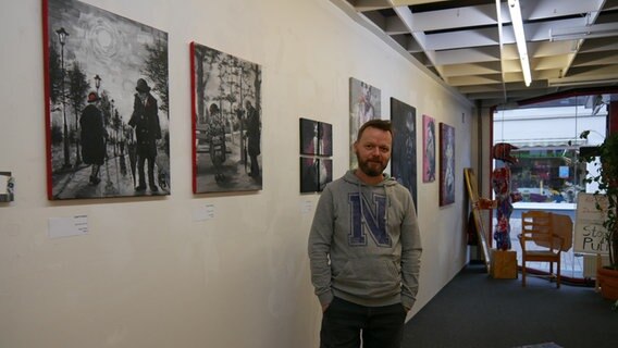Ein Mann steht neben einer weißen Wand mit Bildern © Helgard Füchsel Foto: Helgard Füchsel
