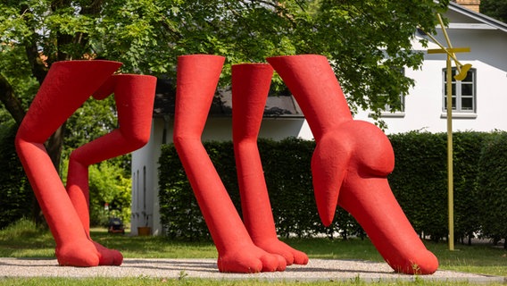 Eine rote überdimensionale Hundeskulptur steht auf dem Rasen. © NordArt / Wohlfromm 