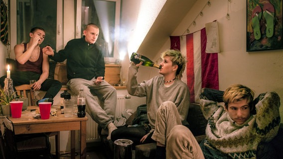 Vier junge Menschen sitzen in einem Zimmer, zwei auf einem Sofa und zwei vor einem Fenster auf einer Fensterbank. © Valentin Goppel Foto: Valentin Goppel