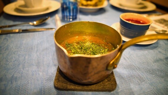 Ein Topf mit Butterbrühe steht auf einem Tisch. © NDR Foto: Tim Piotraschke