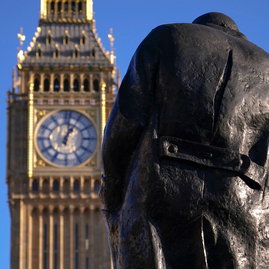 Der Big Ben am Elizabeth Tower in Westminster, London, davor die Statue des ehemaligen britischen Premiers Churchill in Rückenansicht © Foto: Alberto Pezzali/AP/dpa +++ dpa-Bildfunk +++ Foto: Foto: Alberto Pezzali