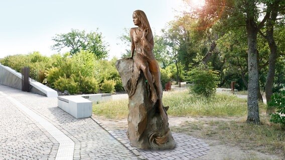 Eine bronzene Skulptur zeigt eine Frau, die auf einem Felsen sitzt und nach unten schaut. © picture alliance/dpa/Verbandsgemeinde Loreley | --- 
