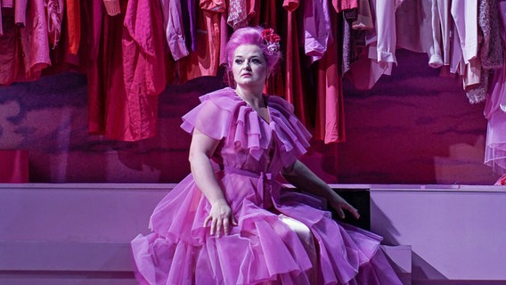 Agnieszka Hauzer (Manon) in einem rosa Kleid vor einem rosa Kleiderschrank. © Staatsoper Kiel 