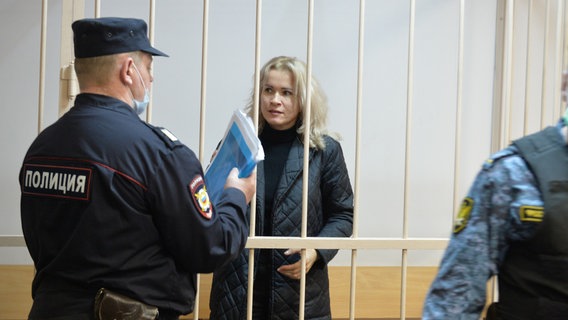 Die Journalistin Maria Ponomarenko hinter Gittern mit zwei Wärtern im Vordergrund. © picture alliance/dpa/Individual contributors Foto: Andrei Bok