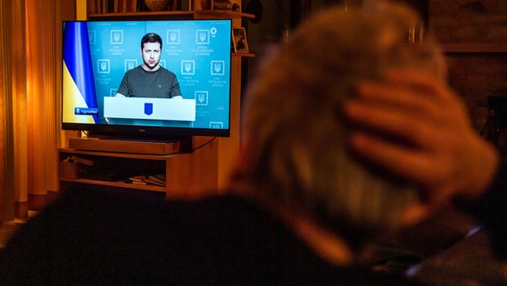 Ein Mann auf dem Sofa schaut im Fernsehen die "Tagesschau" zum Ukraine-Konflikt © picture alliance/dpa Foto: Lino Mirgeler