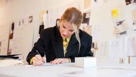 Auf dem Bild ist die Designerin Christina Fassbender zu sehen, die gerade in ihrem Pop-Up-Store in der Hamburger Innenstadt über einer Zeichnung sitzt. © NDR Foto: Susanne Baade