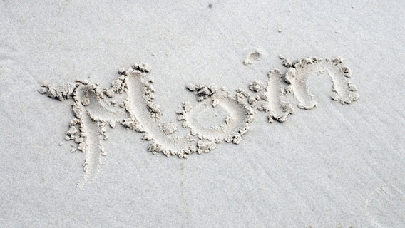 Das Wort "Moin" im Sand von Amrum geschrieben. © picture alliance / Westend61 | Westend61 / Anja Weber-Decker Foto: Anja Weber-Decker