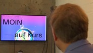 Eine Person sitzt vor einem Bildschirm, auf diesem steht "Moin auf Kurs" © NDR Screenshot 