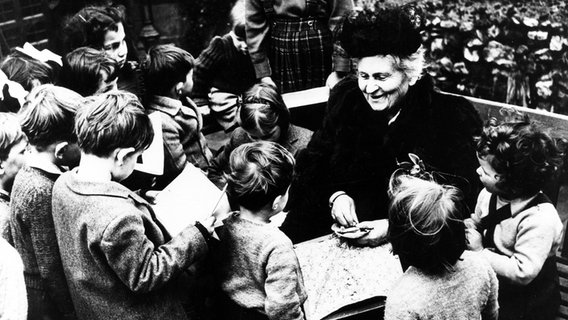 Maria Montessori sitzt in einer Gruppe von Kindern. © picture alliance / ASSOCIATED PRESS 