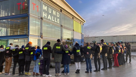 Mitglieder der Genossenschaft bilden eine Menschenkette vor der Mundhalle. © NDR Foto: Antonia Reiff