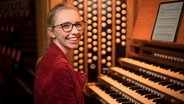Eine junge Frau mit Brille und langen Haaren lächelt glücklich am Pult einer Orgel © Nick Rutter Foto: Nick Rutter