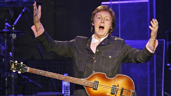 Paul McCartney mit Bassgitarre reißt die Arme bei einem Konzert 2009 in Arnheim/Niederlande hoch ©  Pa/PA Wire/dpa 