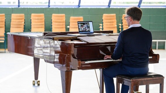 Mann sitzt am Klavier, auf dem ein Laptop mit Videokonferenz steht © picture alliance/dpa | Sebastian Gollnow 