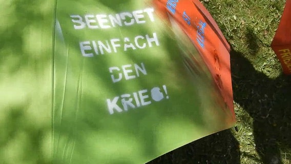 Auf einem Regenschirm steht "Beendet einfach den Krieg" © NDR 