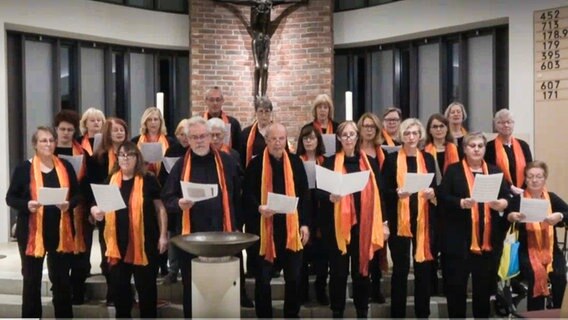 Ein gemischter Chor mit etwa zwanzig Mitgliedern singt in einer Kirche vor dem Altar © NDR 