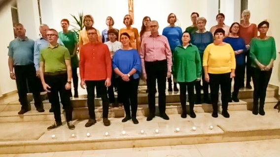 Ein gemischter Chor in verschiedenfarbigen Hemden und Blusen steht vor einem Altar © NDR 