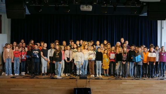 Etwa sechzig Kinder und Jugendliche stehen auf einer Bühne und singen © NDR 