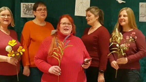 Fünf rot gekleidete Frauen halten Blumen und Gräser in der Hand und singen © NDR 