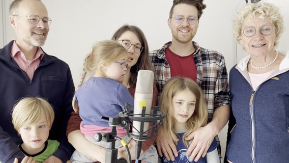 Eine siebenköpfige Familie - Eltern, zwei Großeltern und drei Kinder - hat sich um ein Mikrofon gruppiert und singt. © NDR 