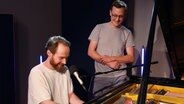 Enno Bunger spielt Flügel und singt im Studio von NDR Kultur Live EXTRA, daneben steht NDR Kultur Redakteur Jan Wiedemann (rechts) © NDR Foto: Tim Piotraschke