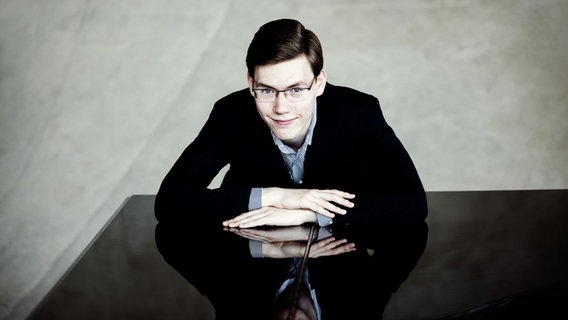 Pianist Roman Fediurko lehnt auf einem Klavier und guckt in die Kamera © Julia Wesely 
