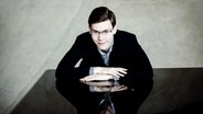 Pianist Roman Fediurko lehnt auf einem Klavier und guckt in die Kamera © Julia Wesely 