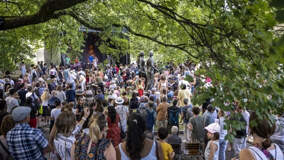 Publikum vor einer Bühne in einem Park während der Fête de la musique © picture alliance/KEYSTONE | MARTIAL TREZZINI 