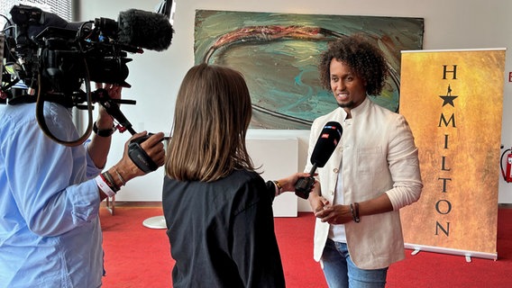 Musical-Darsteller Benét Monteiro beim Pressetermin von "Hamilton" in Hamburg in einem Fernseh-Interview in Hamburg © NDR Foto: Patricia Batlle