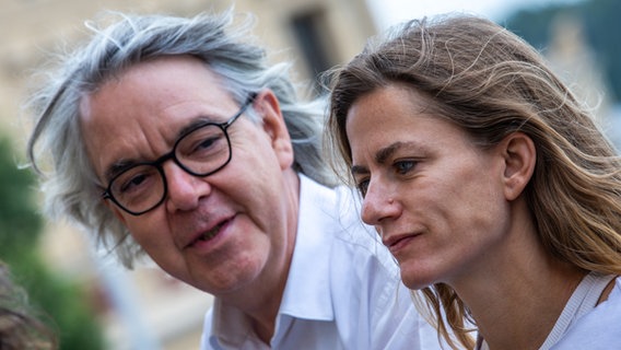 Ein Mann mit Brille und eine Frau mit langen Haaren sprechen miteinander - Performance-Künstlerin Florentina Holzinger und Hans-Georg Wegner, dem Generalintendant des Mecklenburgischen Staatstheaters Ein Mann mit Brille und eine Frau mit langen Haaren sprechen miteinander - Performance-Künstlerin Florentina Holzinger und Hans-Georg Wegner, dem Generalintendant des Mecklenburgischen Staatstheaters © Jens Büttner/dpa +++ dpa-Bildfunk +++ Foto: Jens Büttner