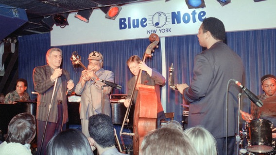 Eine Gruppe von Männern mit Musikinstrumenten spielt auf einer Jazzclubbühne vor Publikum. © picture alliance / ASSOCIATED PRESS | Ali Foto: Ali