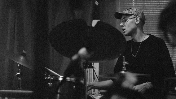 Ein Schwarz-Weiß-Foto von einem Schlagzeug spielenden Mann. © Anna Powell Denton Foto: Anna Powell Denton