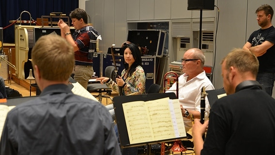 Chefdirigent Jörg Achim Keller (links stehend), Erhu-Spielerin Ma Xiaohui un Posaunist Nils Landgren (sitzend von links), inmitten der NDR Bigband am 13.08.2012 in Hamburg. © NDR Foto: Philip Artus