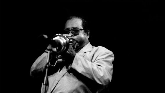 Ein Schwarz-Weiß-Foto von einem Trompete spielenden Mann mit Sonnenbrille © picture alliance / Heritage Images | Jazz Services Foto: picture alliance / Heritage Images | Jazz Services
