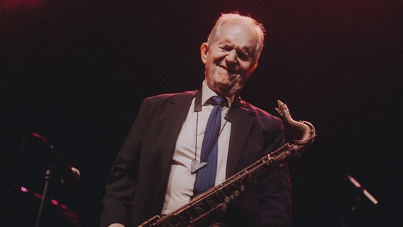 Ein Mann mit Saxofon steht mit geschlossenen Augen auf einer Bühne © Christoph Eisenmenger Foto: Christoph Eisenmenger