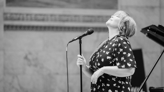 Eine Frau steht mit geschlossenen Augen vor einem Mikrofon auf einer Bühne. © Tore Sætre // CC BY-SA 4.0 DEED Foto: Tore Sætre (http://www.setre.net/)