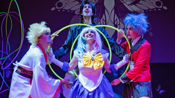 Vier Opernsänger in bunten Kleidern mit leuchtenden Hula-Hoop-Reifen auf der Bühne. © Inken Rahardt/ Opernloft Foto: Inken Rahardt